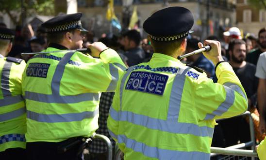 Police officers stand with their batons raised as anti-Erdogan protesters stage a demonstration outside Downing Street 