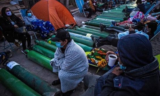 People camp as they wait to refill empty oxygen cylinders in Villa El Salvador, on the southern outskirts of Lima, on February 25, 2021, amid the COVID-19 coronavirus pandemic