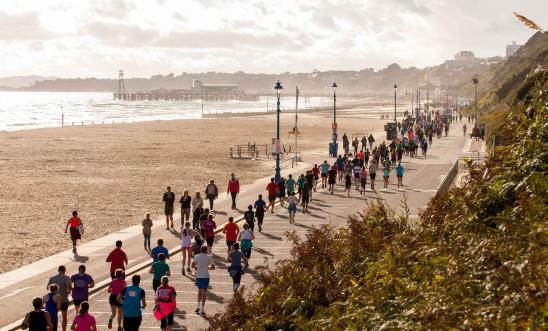 Hundreds of people run alongside a beautiful coastal scene.