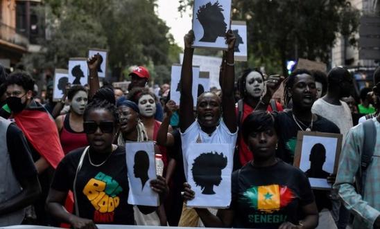 Protestors hold signs depicting silhouettes as they take part in a anti-racism demonstration "against the deaths at the borders" in Barcelona on July 1, 2022