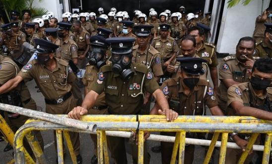 Sri Lanka police stand up against barricades with gas masks to protect themselves from tear gas