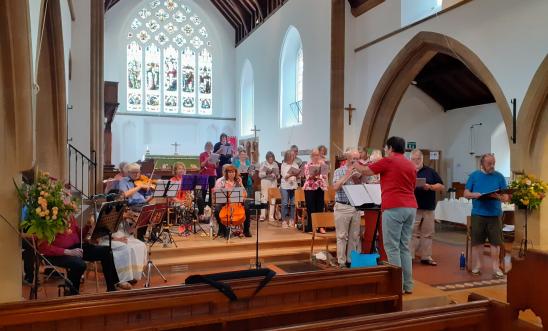 Orchestra, choir and conductor rehearsing in a church