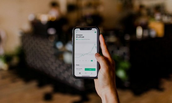 Hand of a person holding a phone showing stocks of a company Hand of a person holding a phone showing stocks of a company