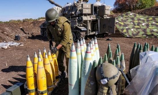 An Israeli army soldier adjusts the tip to a 155mm artillery shell near a self-propelled howitzer An Israeli army soldier adjusts the tip to a 155mm artillery shell near a self-propelled howitzer