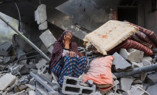 Palestinian woman sat on rubble crying - Gaza