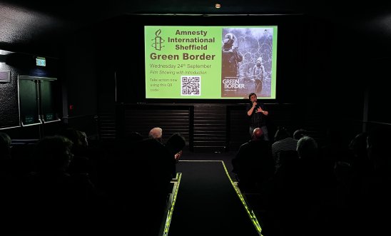 Josh Cheesman, the chairman of Amnesty Sheffield, standing in front of a cinema screen, talking to audience members before the showing of Green Border Josh Cheesman, the chairman of Amnesty Sheffield, standing in front of a cinema screen, talking to audience members before the showing of Green Border