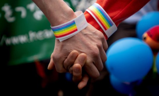 Two people hold hands in solidarity with LGBTQ+ rights