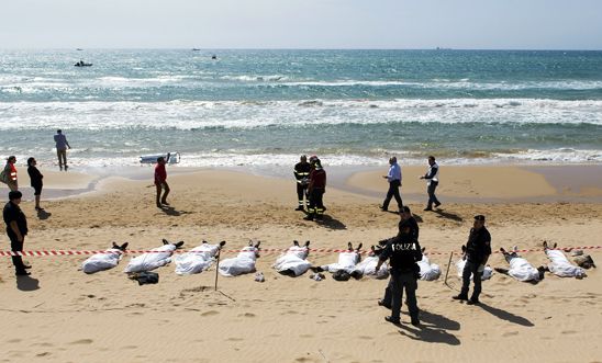 Rescue workers stand next to bodies of migrants who drowned off the coast of Sam