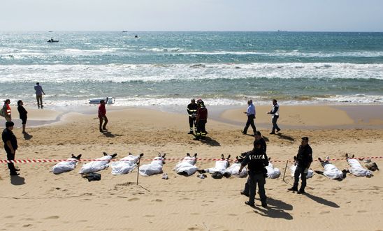 Rescue workers stand next to bodies of migrants who drowned off the coast of Sam Rescue workers stand next to bodies of migrants who drowned off the coast of Sam