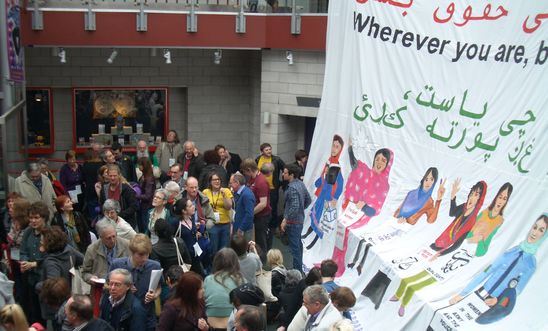 Large banner of women's rights in Afghanistan with conference delegates