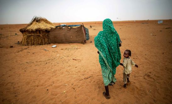 A woman and her child approach their home in Darfur, Sudan. A woman and her child approach their home in Darfur, Sudan.