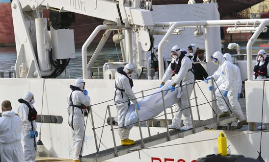 Crew from an Italian Coast Guard ship disembark one of the estimated 700 victms Crew from an Italian Coast Guard ship disembark one of the estimated 700 victms