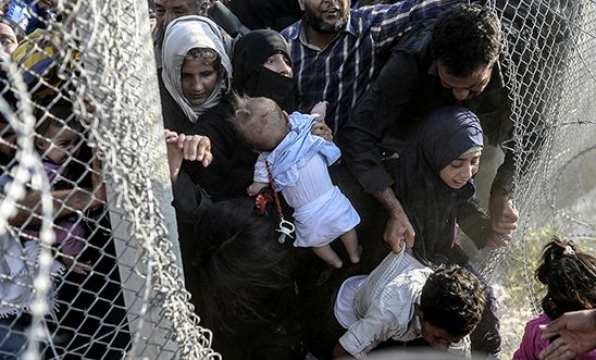 Syrians fleeing the war rush through broken down border fences to enter Turkey.