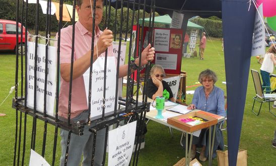 PIcture of Amnesty member in a cage, beside our stall