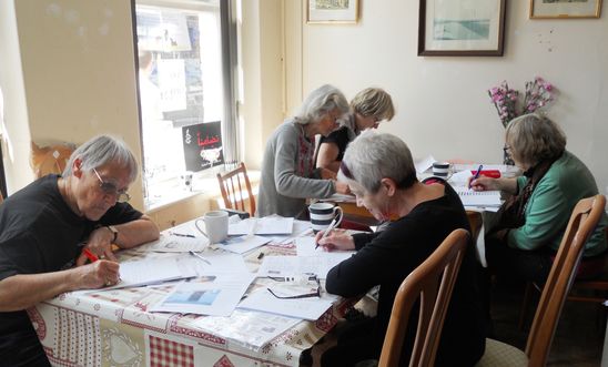 Members sitting round tables writing letters