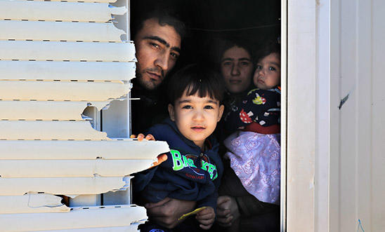 A family peeks through the window of the shipping container that is their temporary home A family peeks through the window of the shipping container that is their temporary home