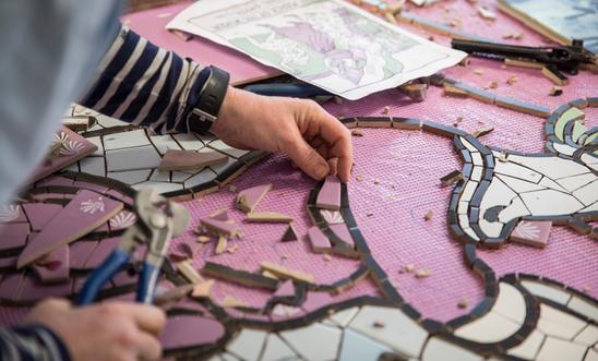The artist's hand places ceramic pieces in a mural The artist's hand places ceramic pieces in a mural