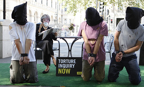 A stunt outside Downing street depicting Theresa May ignoring torture victims kneeling in front of her. A stunt outside Downing street depicting Theresa May ignoring torture victims kneeling in front of her.