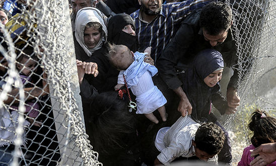 Syrians fleeing the war rush through broken down border fences to enter Turkey. Syrians fleeing the war rush through broken down border fences to enter Turkey.