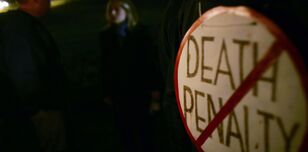 Round placard with the words death penalty struck through with a red stripe