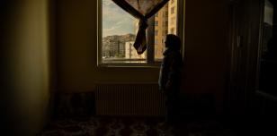Woman looking out of a window in Afghanistan. Photography by Kiana Hayeri