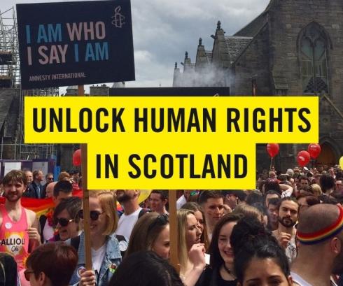 Group of people protesting in a street in Scotland, while the overlay text reads 'Unlock Human Rights in Scotland'