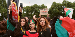 Women in London at a protest for Afghanistan dressed in country colours and holding the flag, Text reads Afghanistan. Stand with women and girls - Photo by Ehimetalor Akhere Unuabona