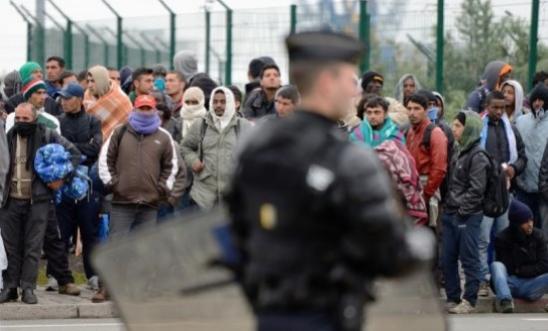 Migrants gather by a fence in Calais Migrants gather by a fence in Calais