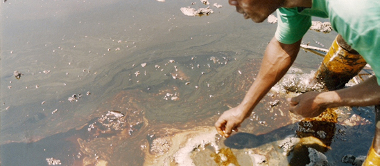 A fisherman stands in the oiled creek of Bodo, Niger Delta